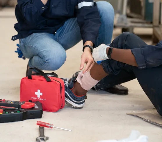 Man with a hurt ankle being bandaged by another man
