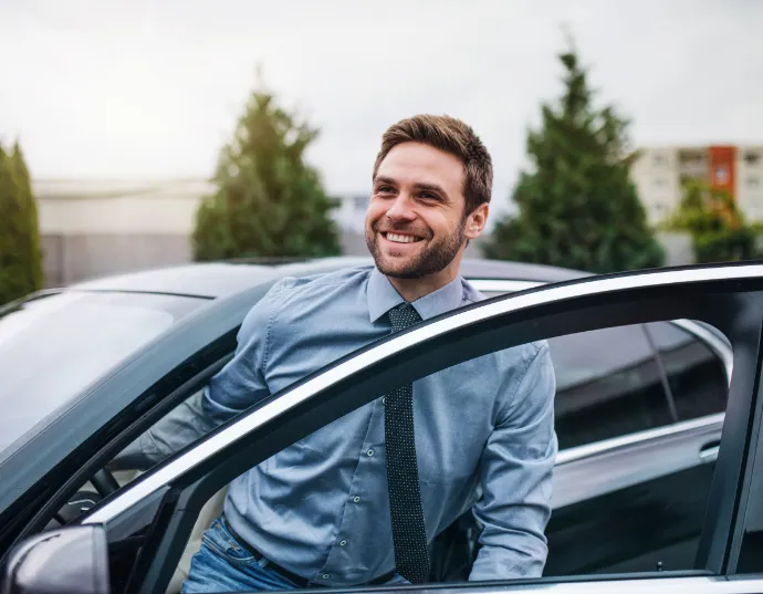 Young man stepping out of his car with a smile